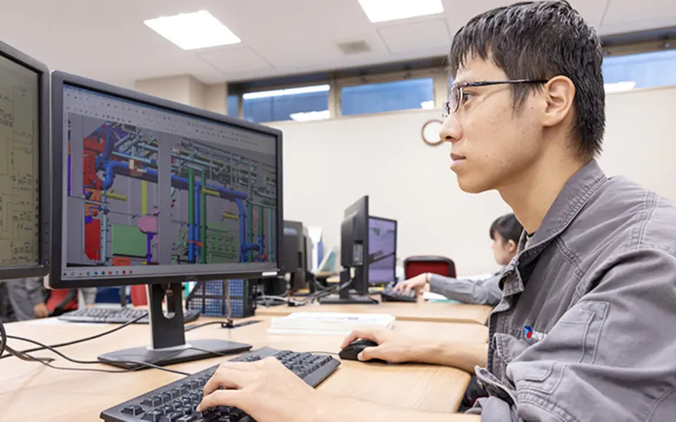 Engineer reviewing a three-dimensional piping model at a CAD workstation
